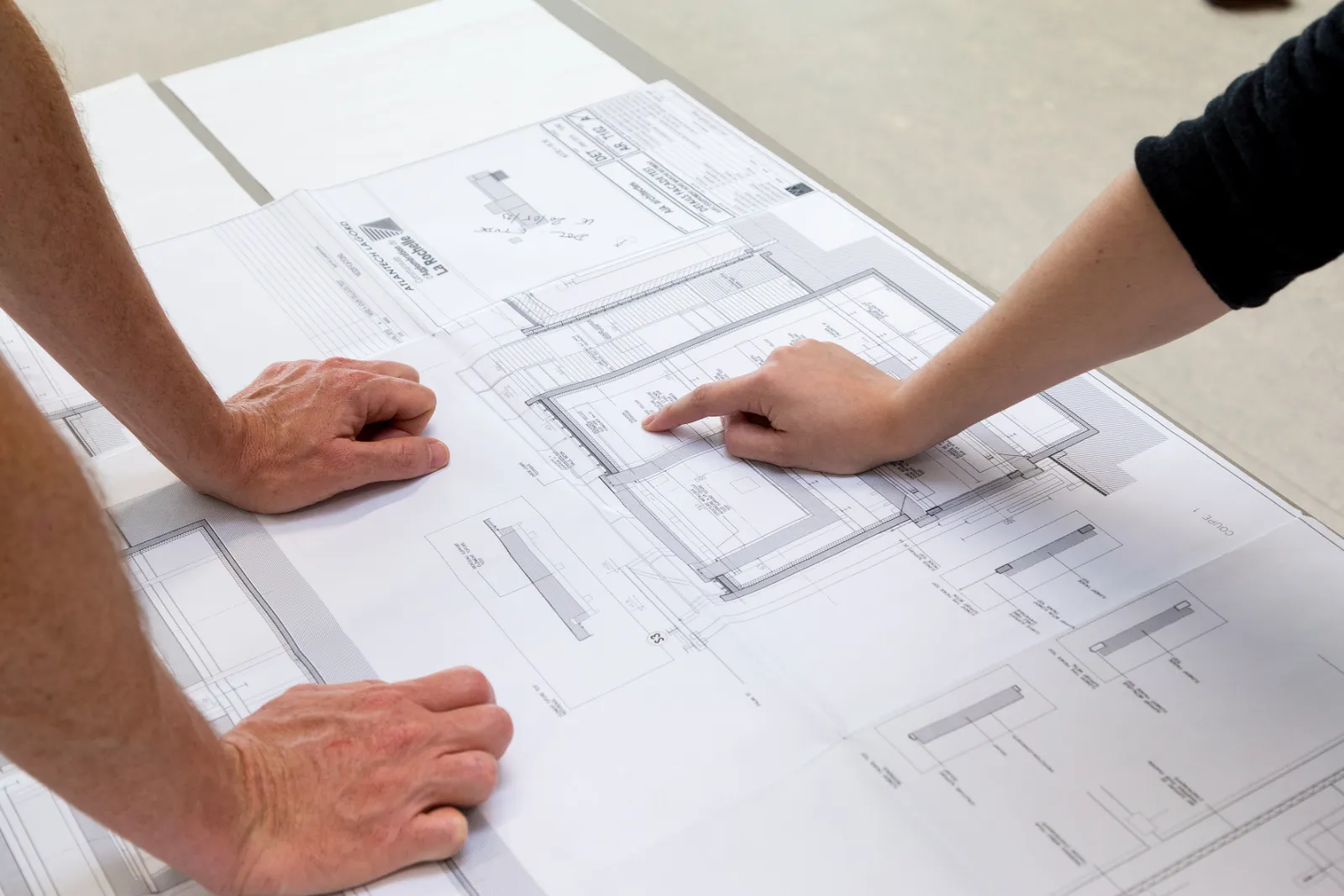 Mains annotant un plan de bâtiment